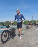 Ein männlicher Triathlet schiebt sein Rad durch die Wechselzone 
